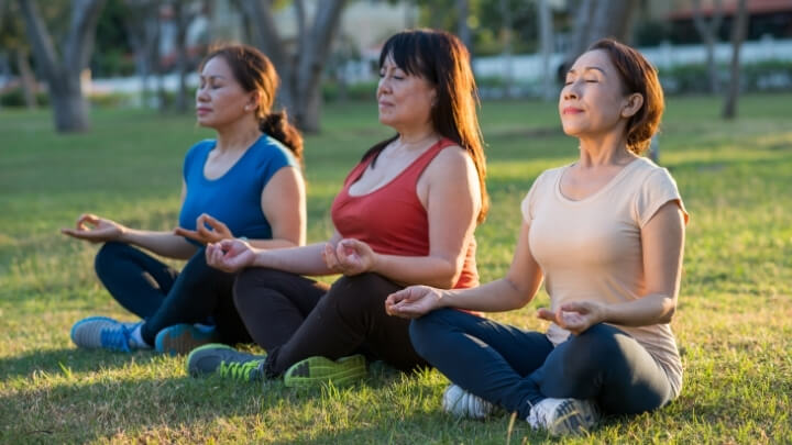 3 women meditating in the park
