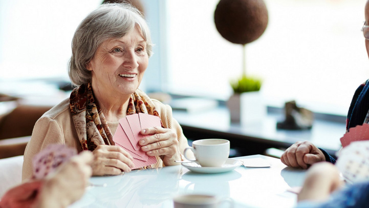 A senior woman playing cards with her friends