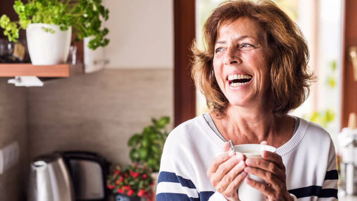 A senior woman laughing in her kitchen