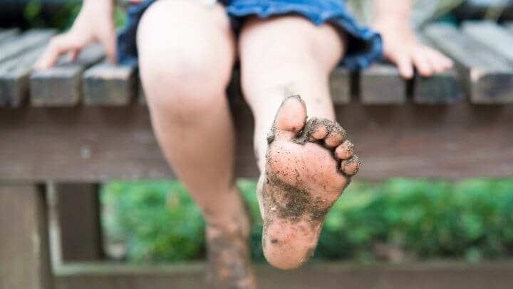 Kid with muddy feet sitting on a dock