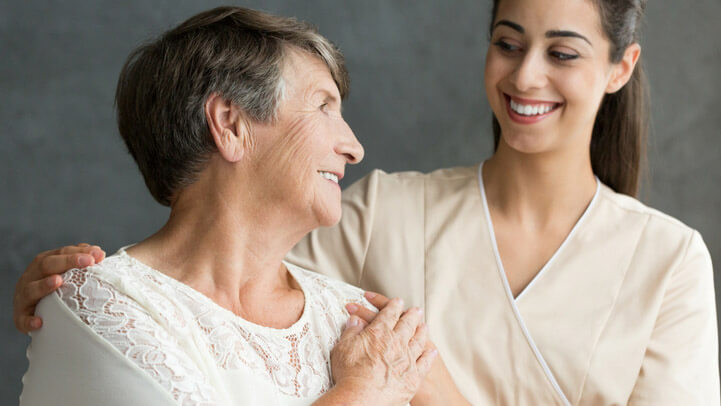 An older woman and a younger woman smiling at each other