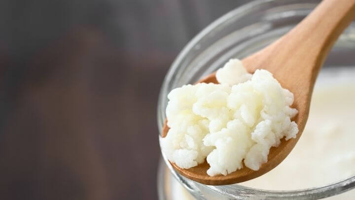 Kefir in a wooden spoon and a mason jar