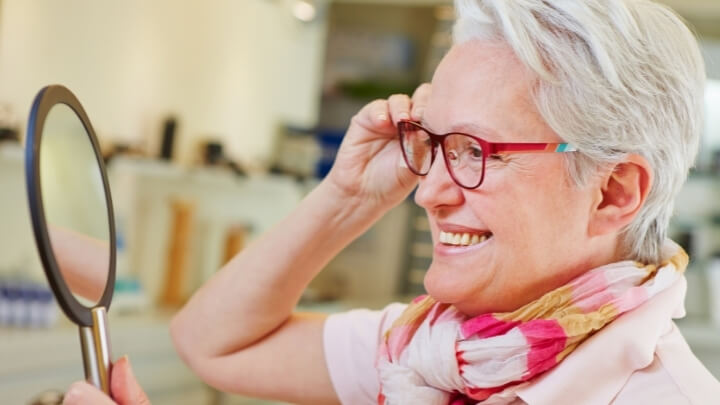 A senior woman checking her new seeing glasses in the mirror