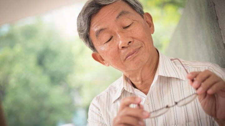 Older man looking at his seeing glasses