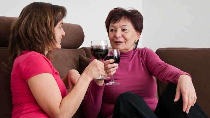 Mother and adult daughter enjoying some wine at home