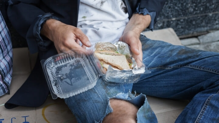 Homeless man eating donated sandwich