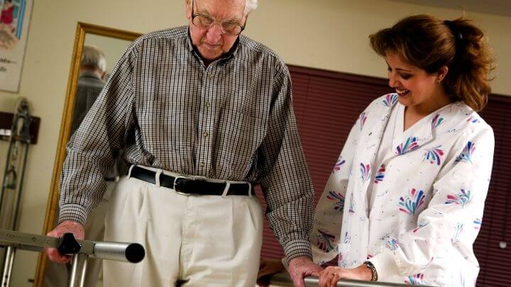 A physical therapist helping an elderly man