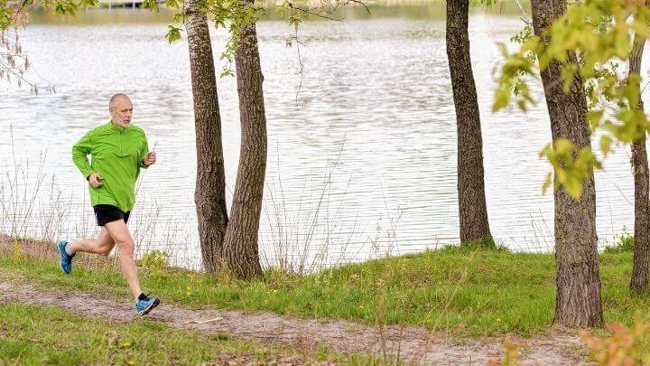 Older man jogging by a lake