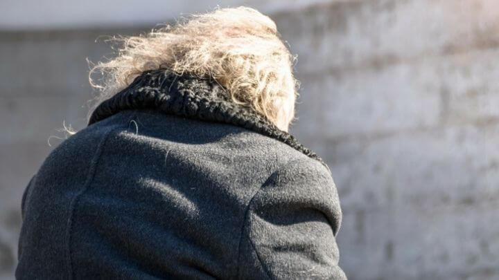 A photo of an older person sitting taken from the back