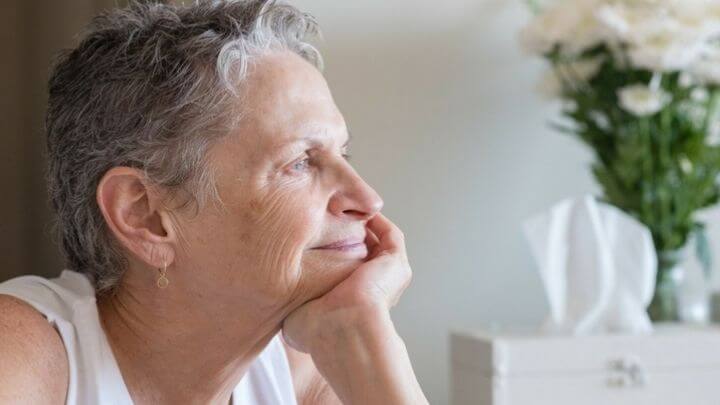 A smiling older woman looking out of the window