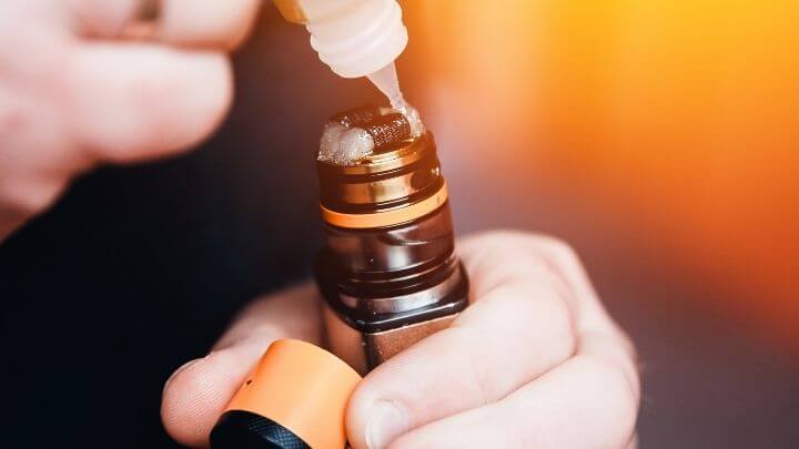 Man applying e-liquid to his vaping device