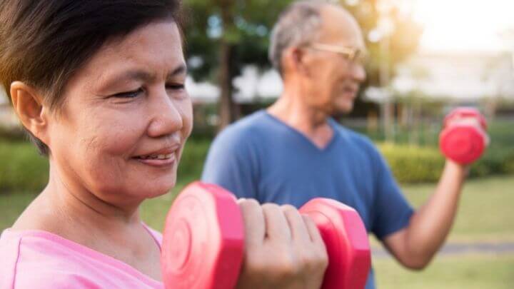 A senior couple working with dumbbells at the park 