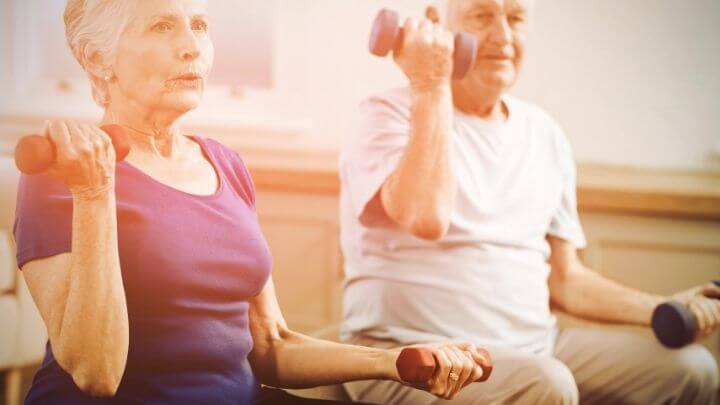 A senior couple working with dumbbells at home 