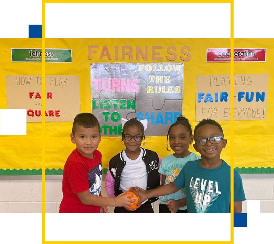 Kids pose in front of art board.