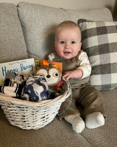 Malcolm on a sofa with stuffed animals.