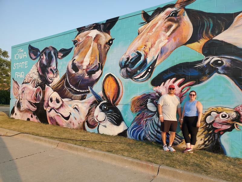 Associate Whitney Free and her husband Joe in front of a mural at the Iowa State Fair