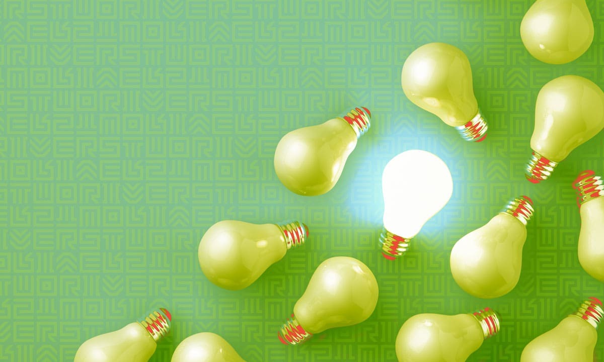 Light bulb glowing with a brainstorming idea among other green light bulbs.