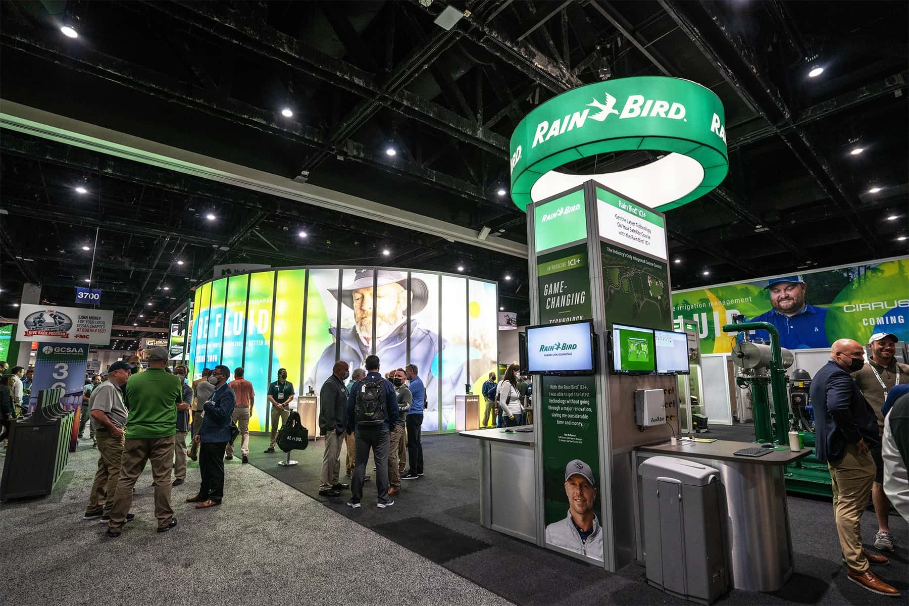 Wide shot of trade show floor where many people are gathering in a booth with Rain Bird branding