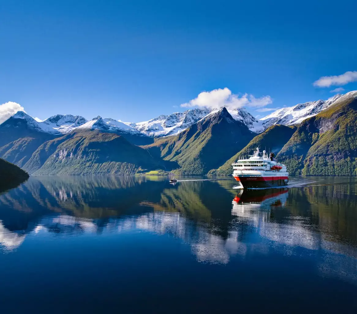 A stunning scenic image of mountains and sea with Hurtigruten ship sailing