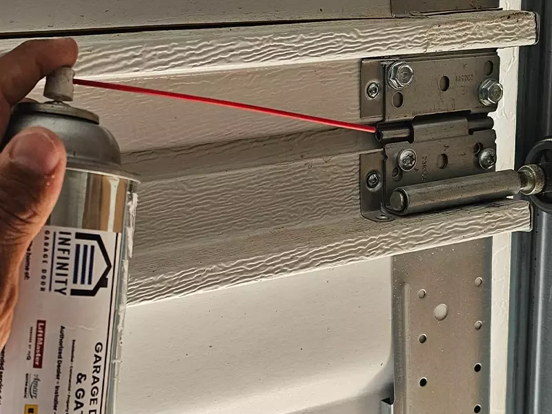 Applying lubricant during garage door roller maintenance in Las Vegas