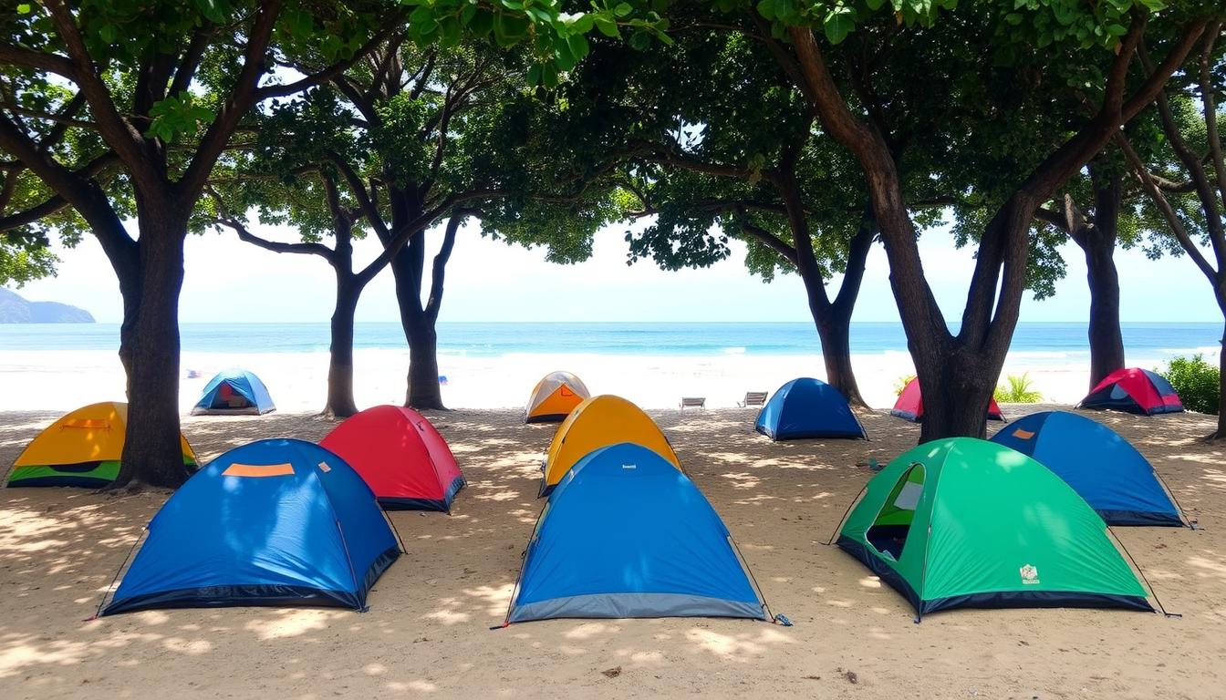 Barracas de camping montadas sob as árvores na Praia do Sono em Paraty, com o mar azul ao fundo