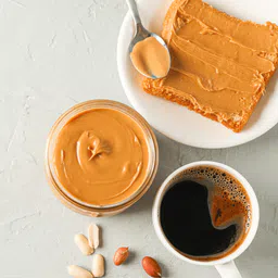 Private label amerpharma peanut butter flavour salted caramel serving suggestion on a sandwich, with cup of coffee