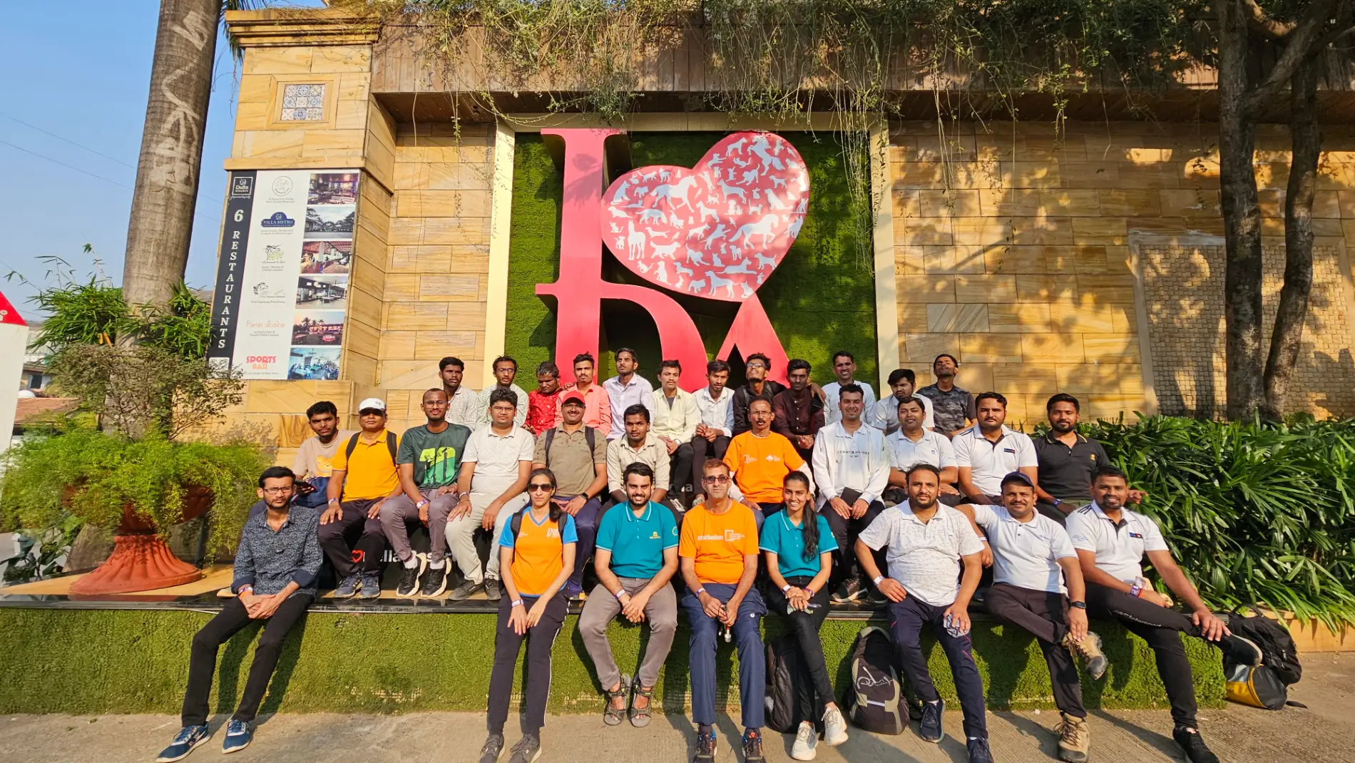 A large group of ABBF volunteers and participants sitting together for a photo in front of a heart sculpture.