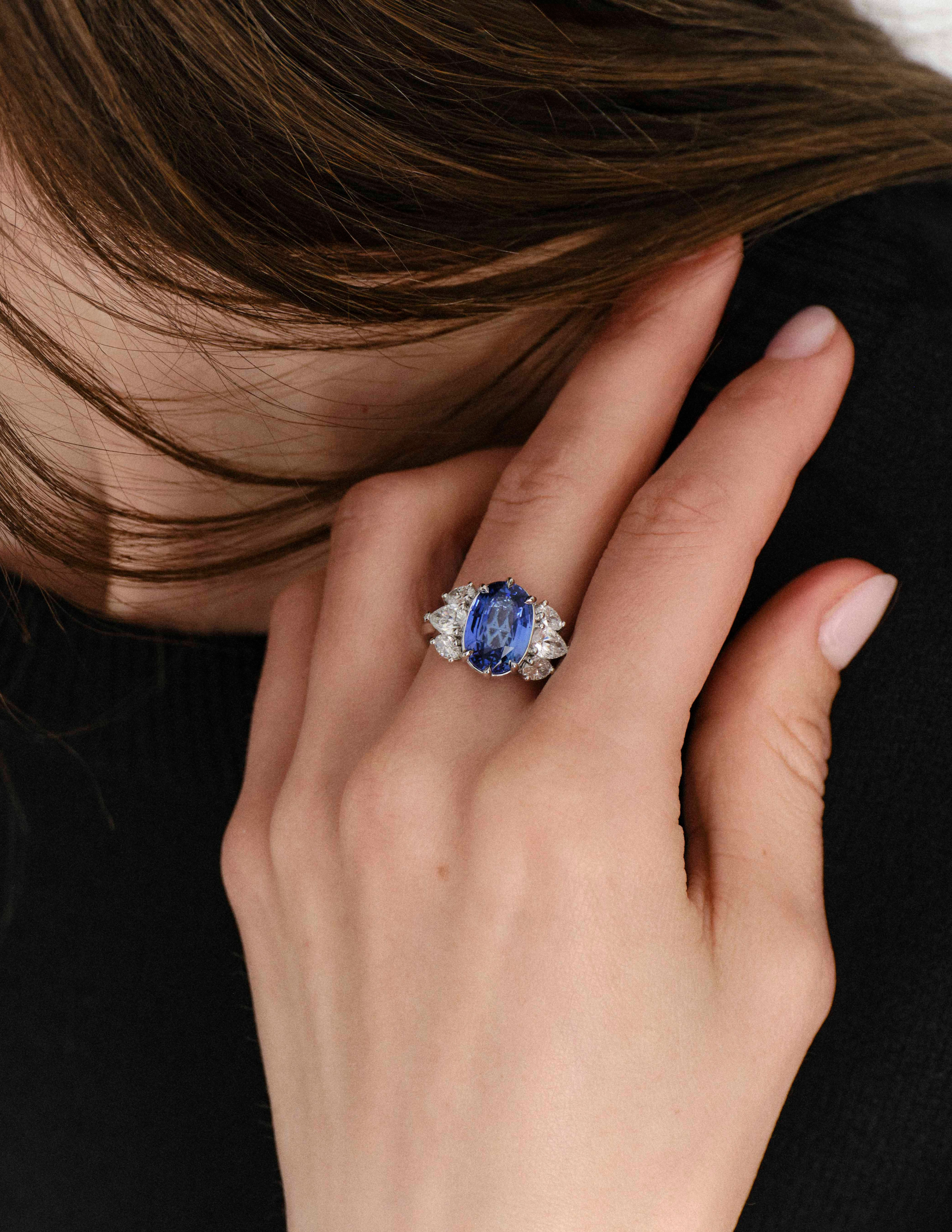 Model wearing an Avermore sapphire and diamond statement ring, photographed in a close-up beauty shot with the hand resting near the face