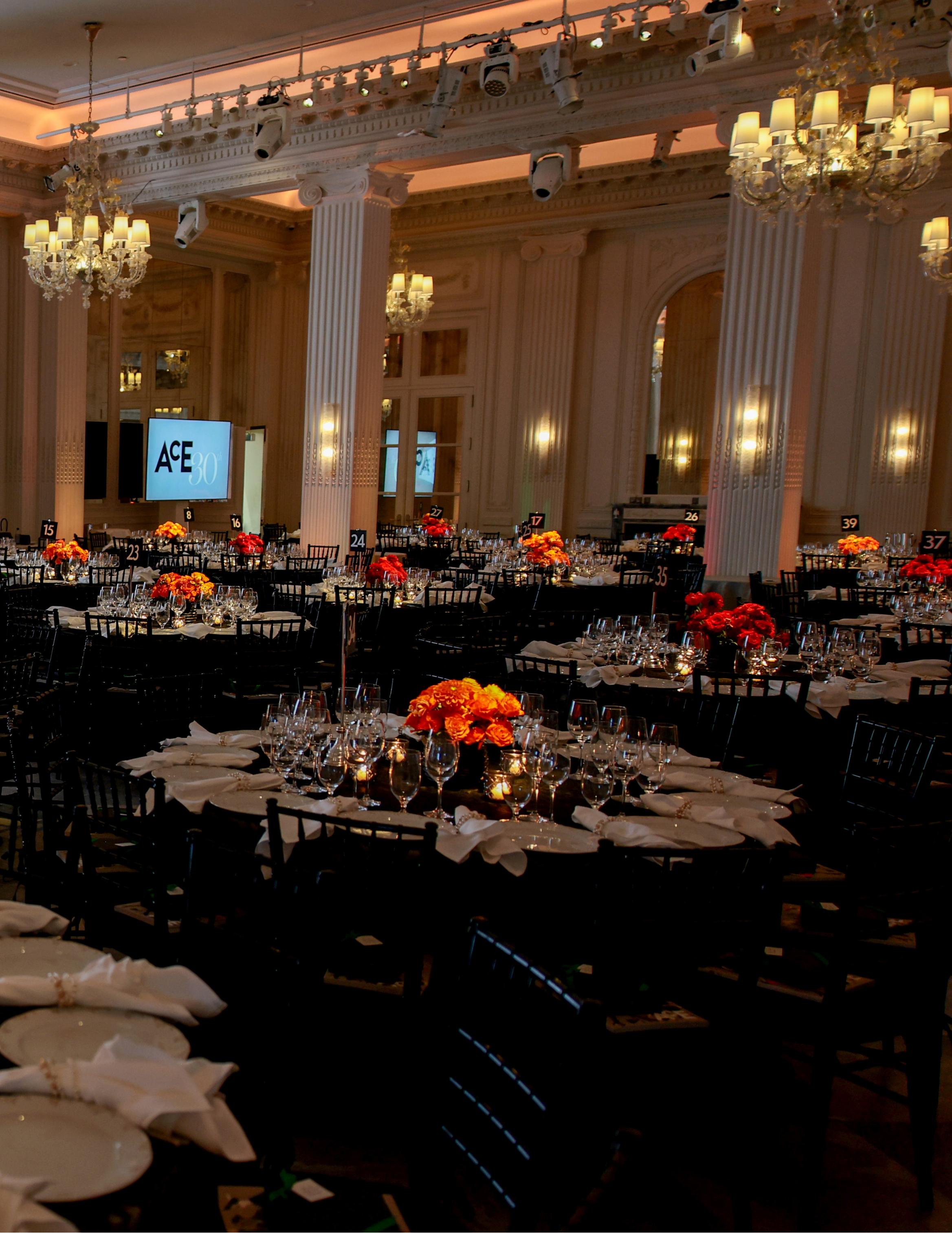 Elegant event ballroom with chandeliers, banquet tables, floral centerpieces, and a stage prepared for the ACE Awards 2026 celebration.