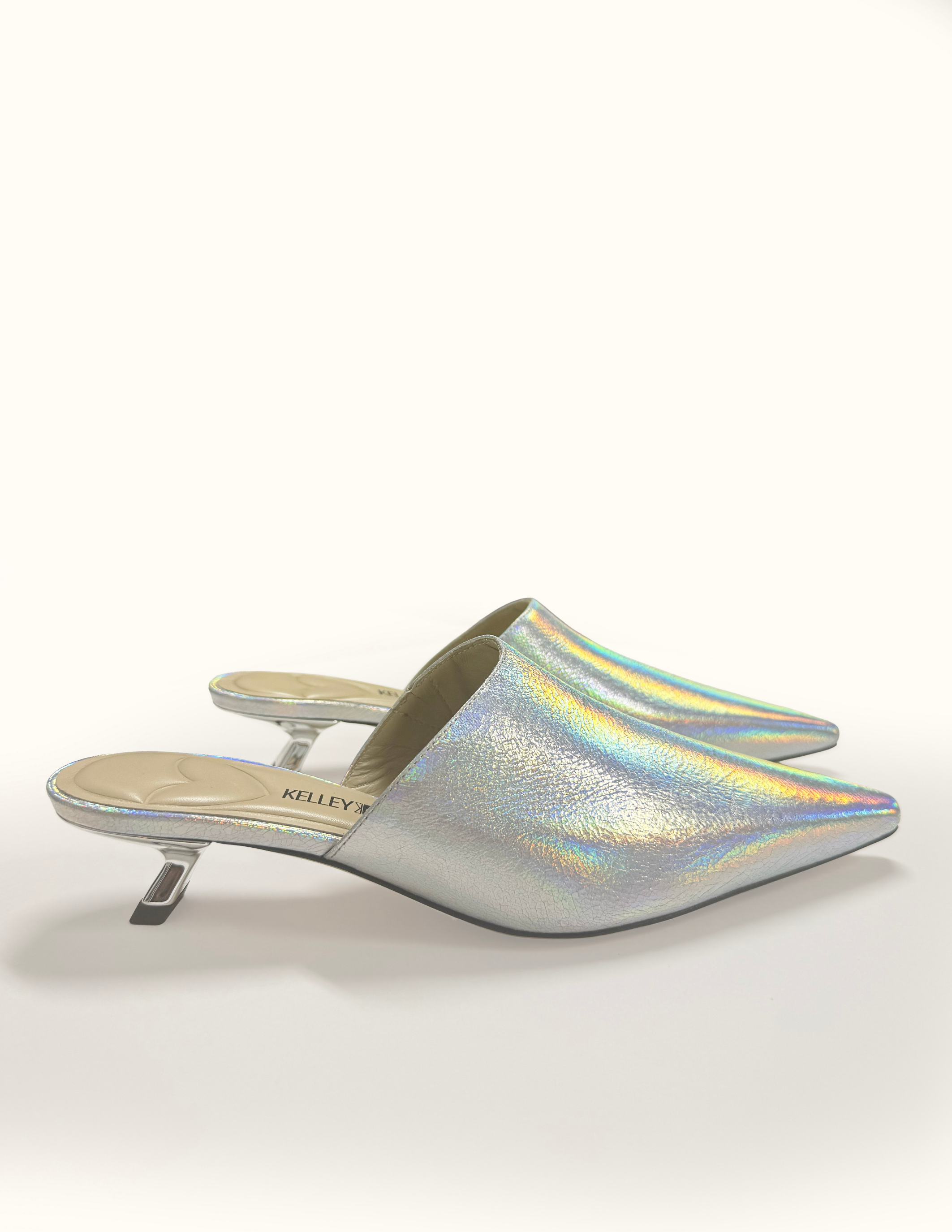 Iridescent silver mules with low heel by Kelley Kouture on a white background