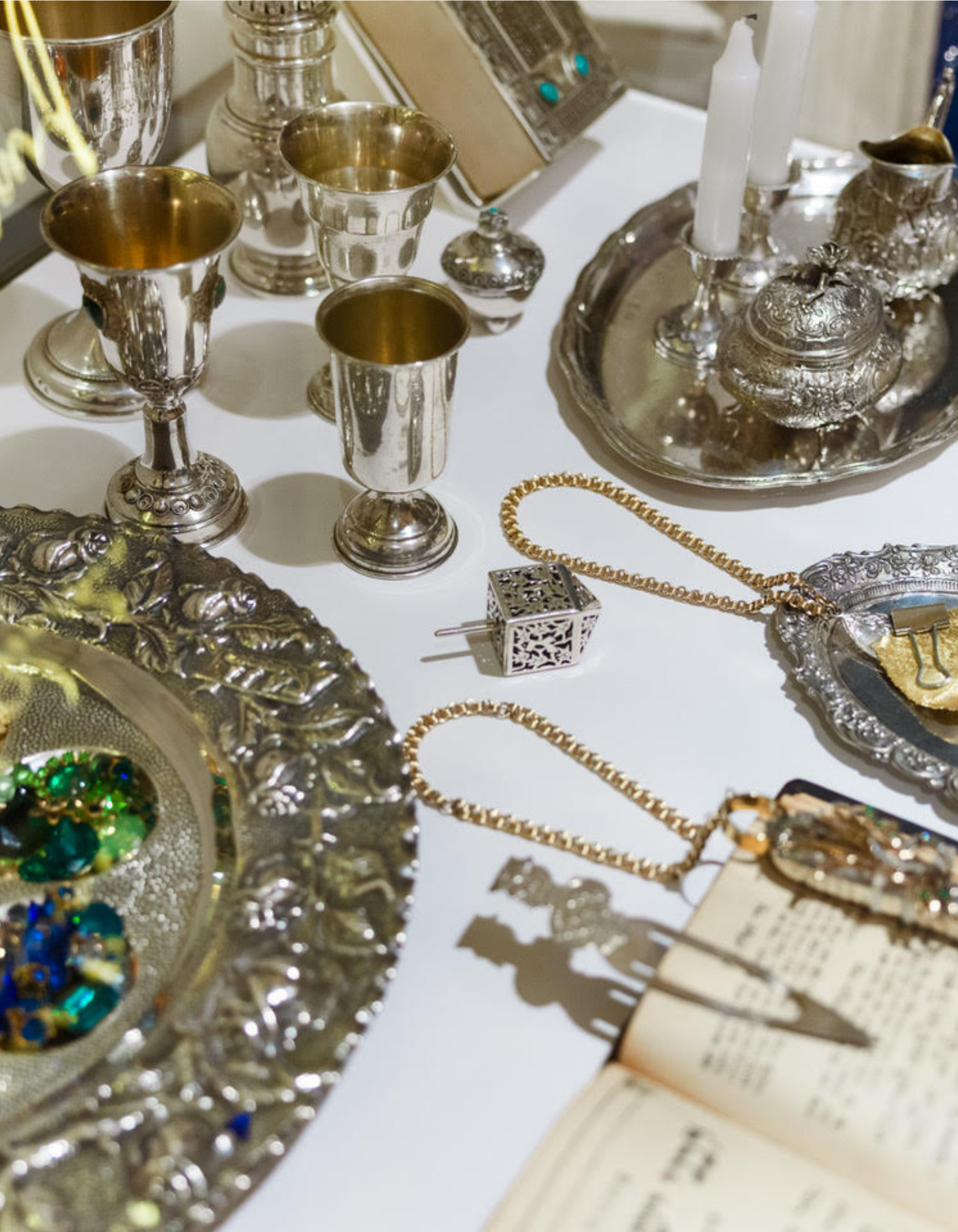 Array of vintage looking items from John Wind Jewelry: cups, trays, gems, chains, candles