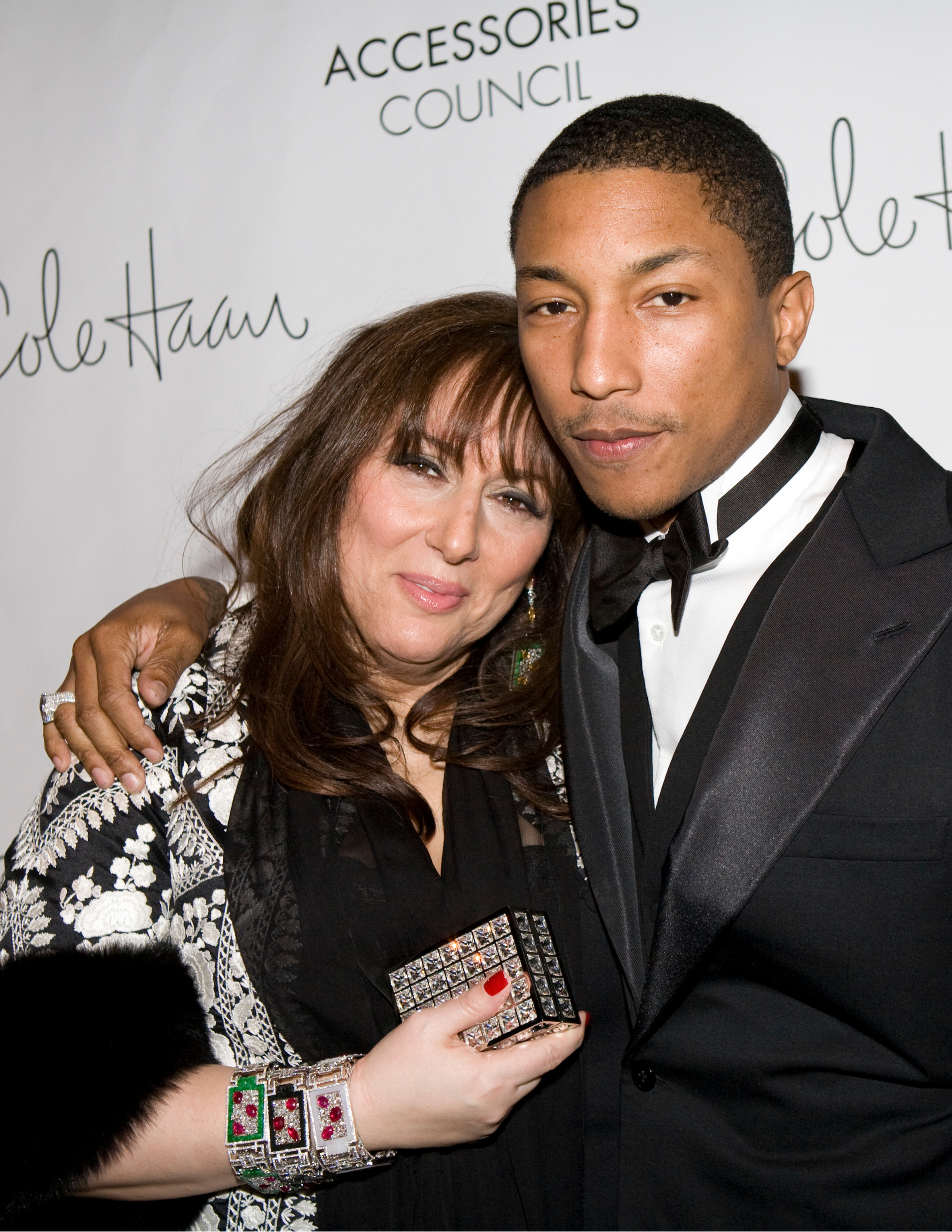 Lorraine Schwartz and Pharrell Williams posing together at an ACE Awards Gala, with Lorraine holding an ACE Award.