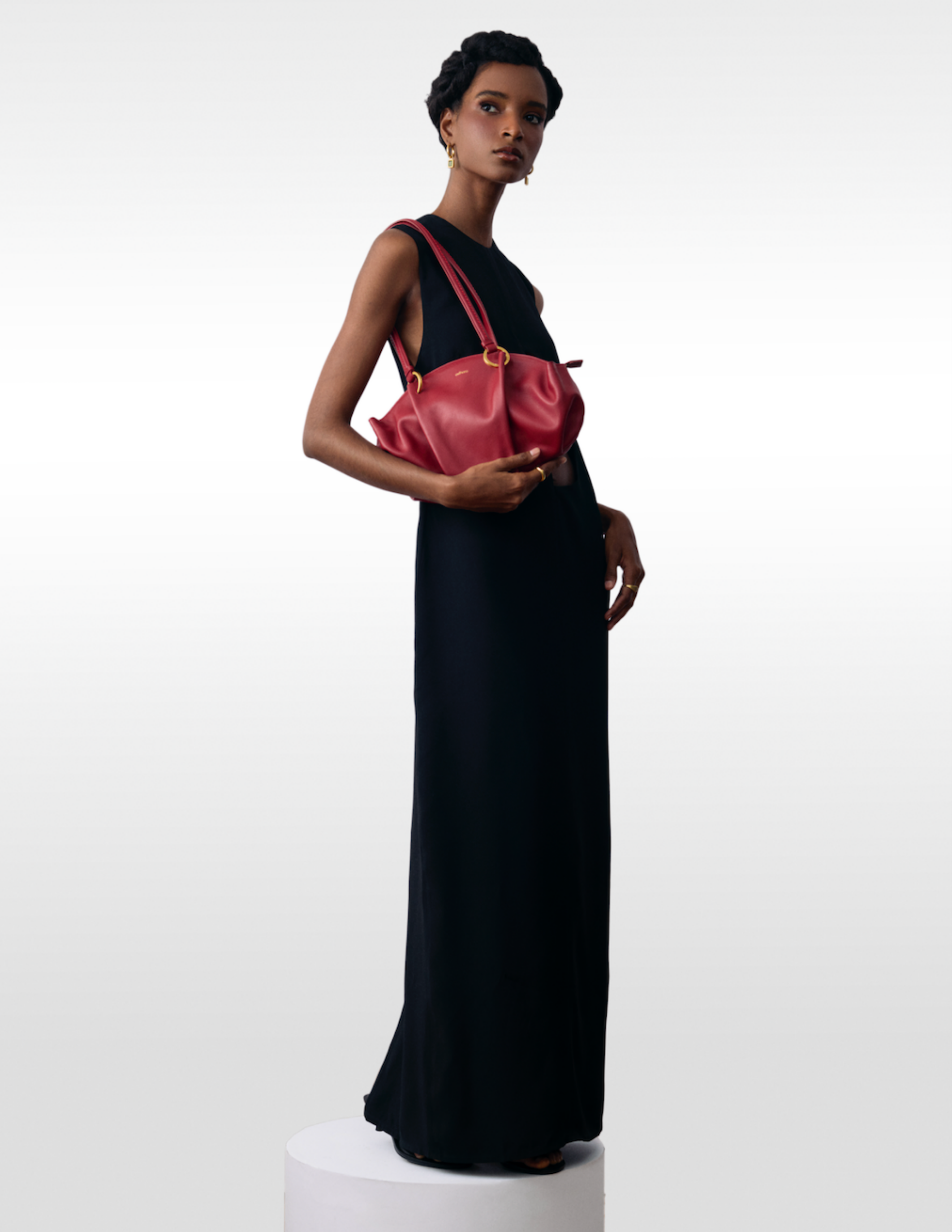 Model wearing a black dress and carrying a burgundy leather shoulder bag by Esthera
