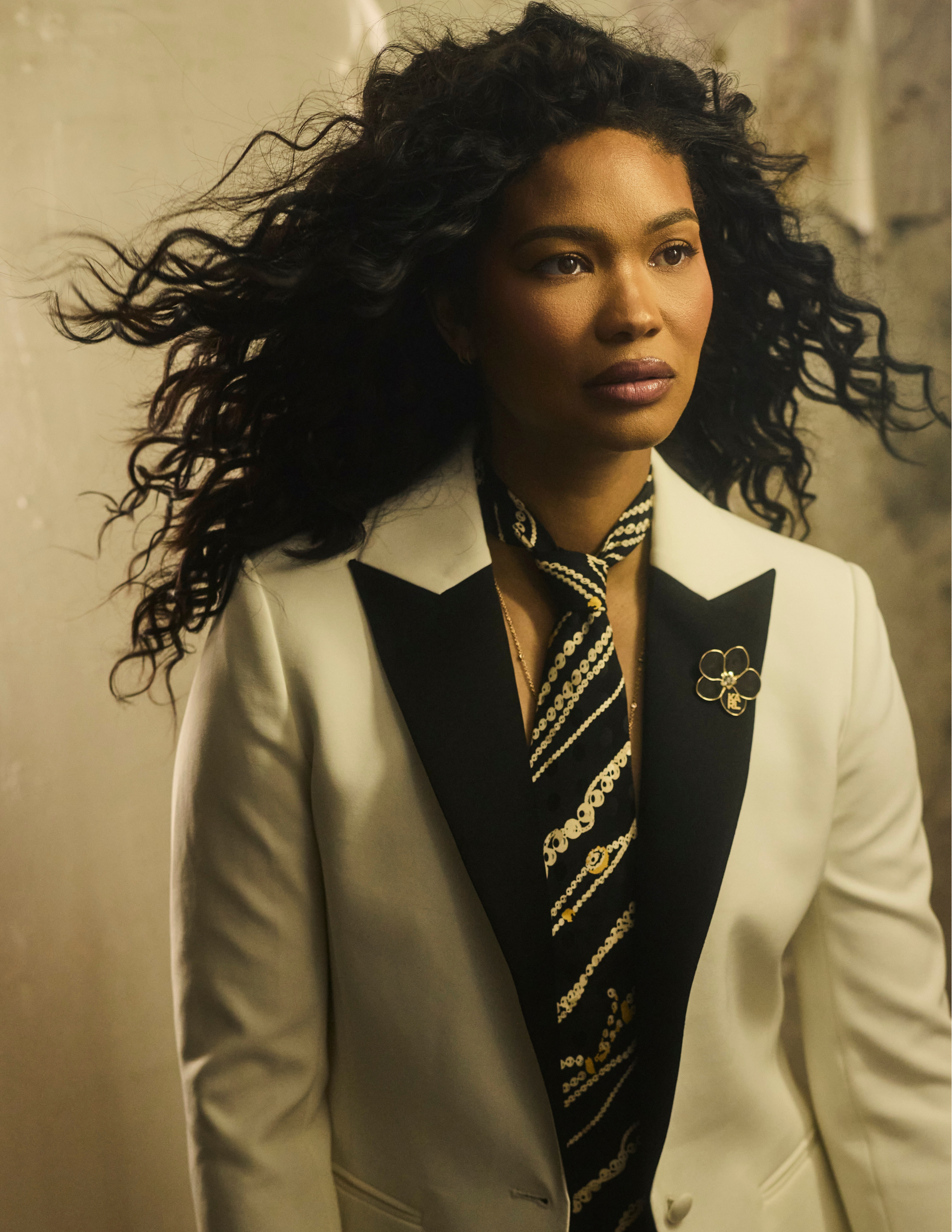 Chanel Iman in a white BCBG Max Azria blazer and Nicole Miller patterned tie with a Karl Lagerfeld lapel pin, close-up portrait with wind-swept hair.