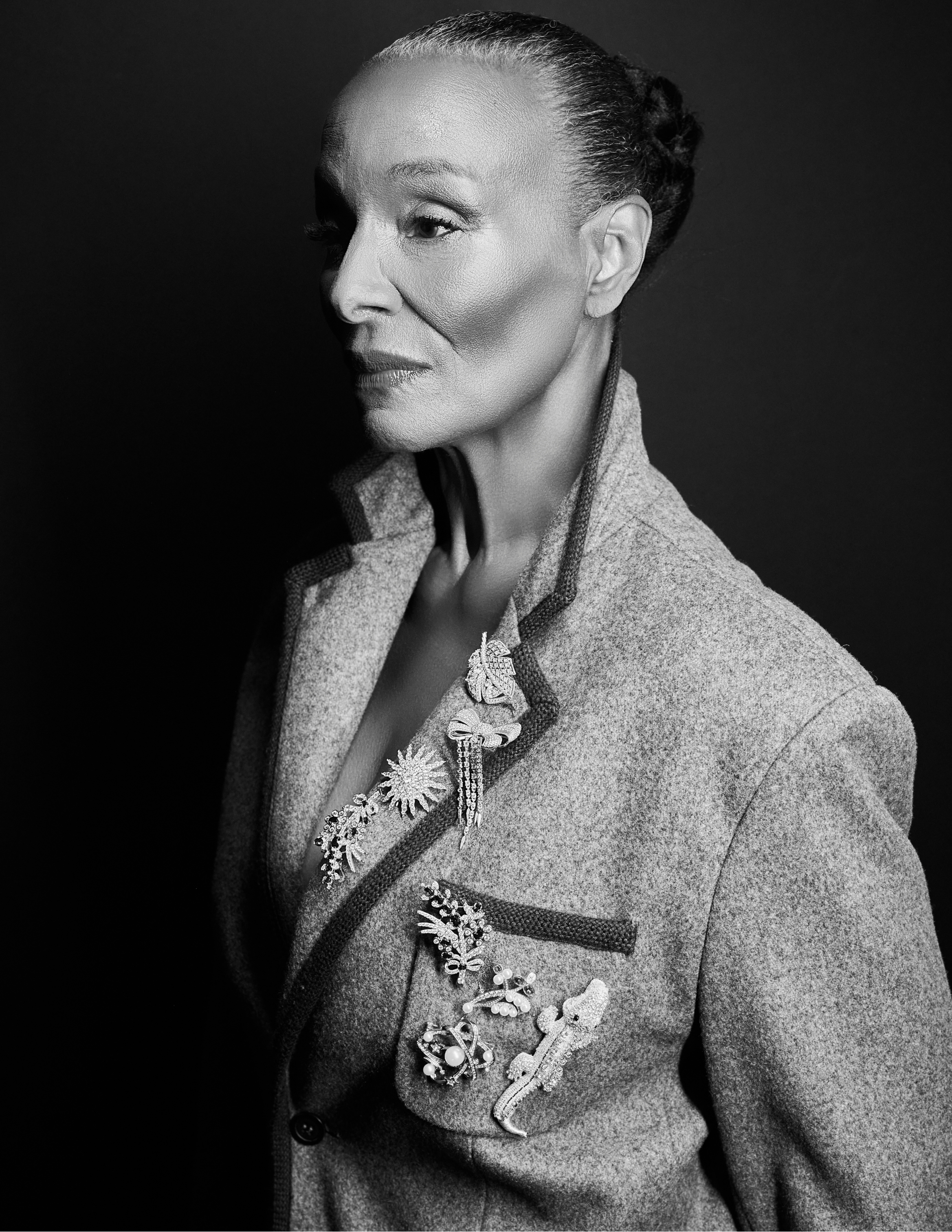 Anedra Shockley-Elsesser in a black and white photo wearing an oversized blazer in dramatic lighting, featuring pins from Elite Group, LGP Gem, and Deepa Gurnani.