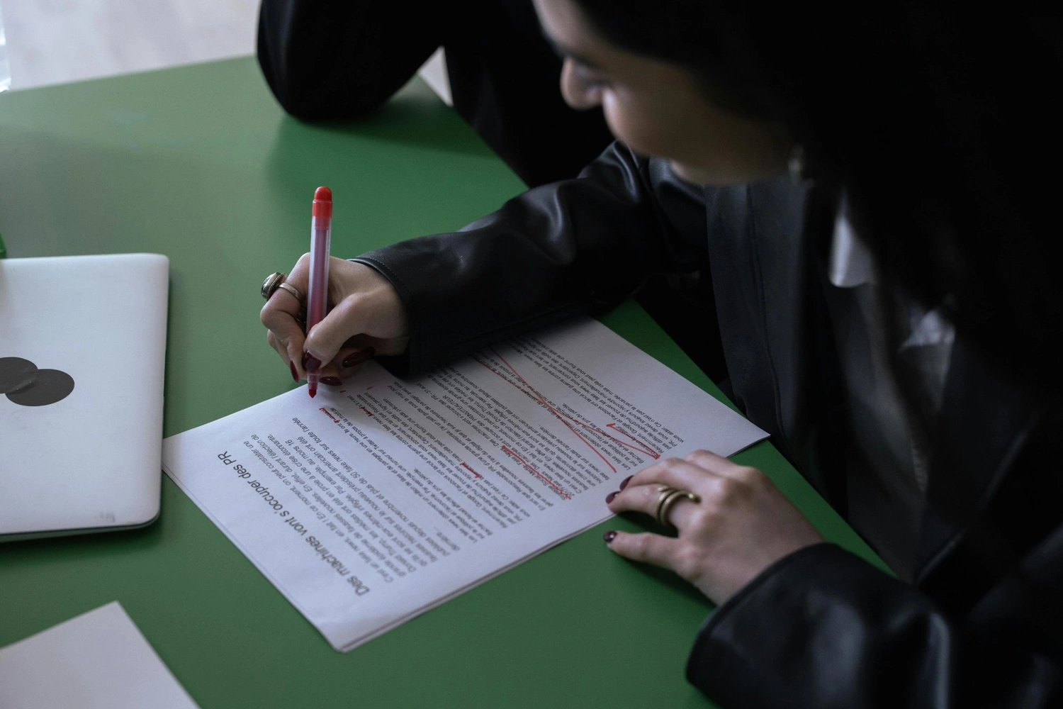 Person editing a manuscript with a red pen, marking corrections on a printed page, illustrating the process of manuscript editing services.