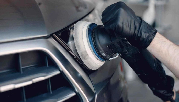 Technician buffing the front of a vehicle