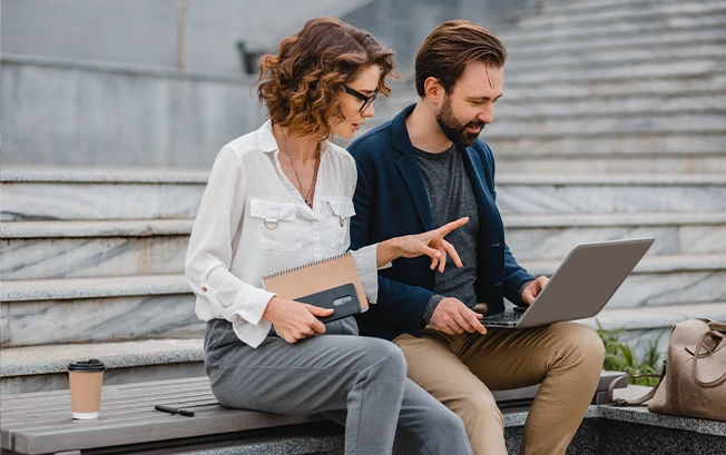 A man and woman holding a laptop and discussing finances