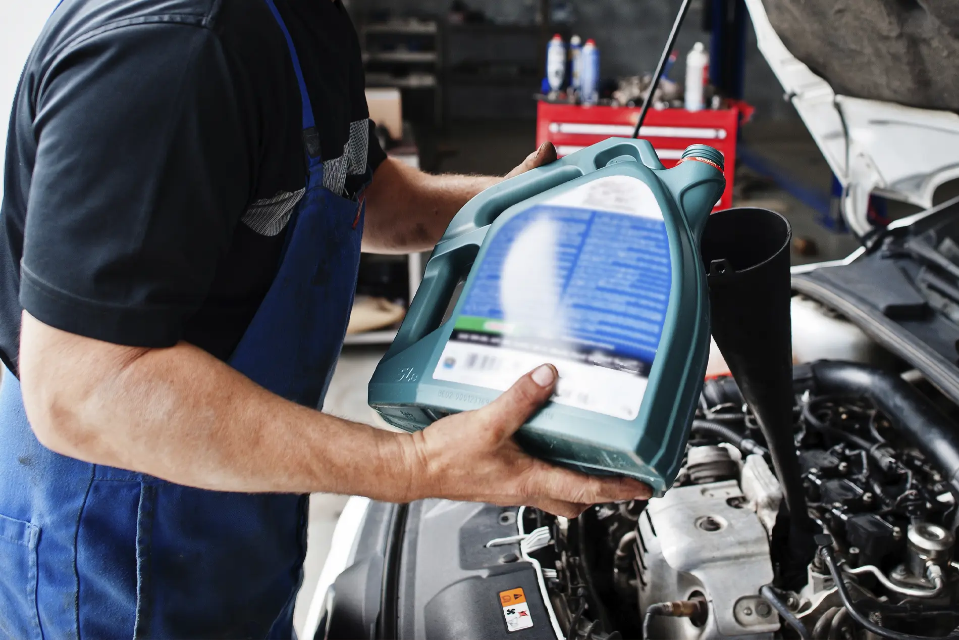 Close up of a technician pouring motor oil into a vehicle