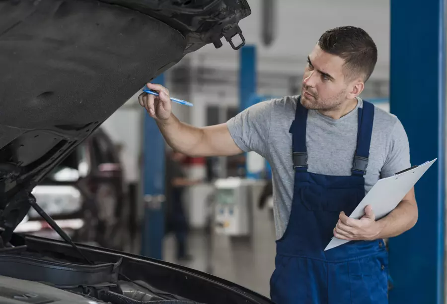 Mechanic looking under the hood taking notes