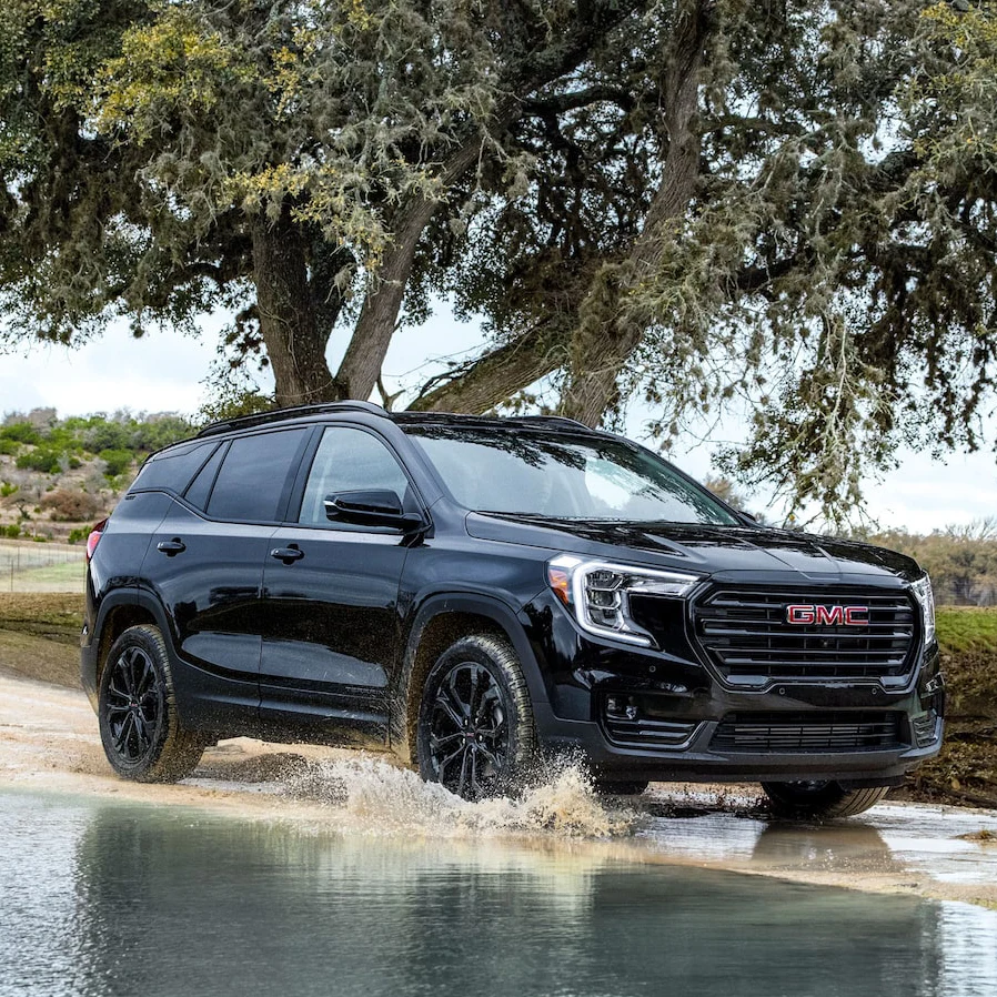 Black 2022 GMC TERRAIN ELEVATION EDITION driving through a puddle