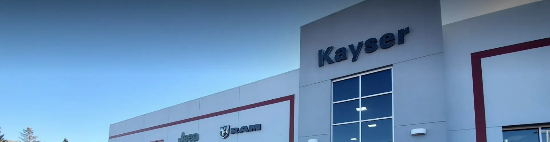 An image of the Kayser Chrysler Center Dealership's entrance and sign.