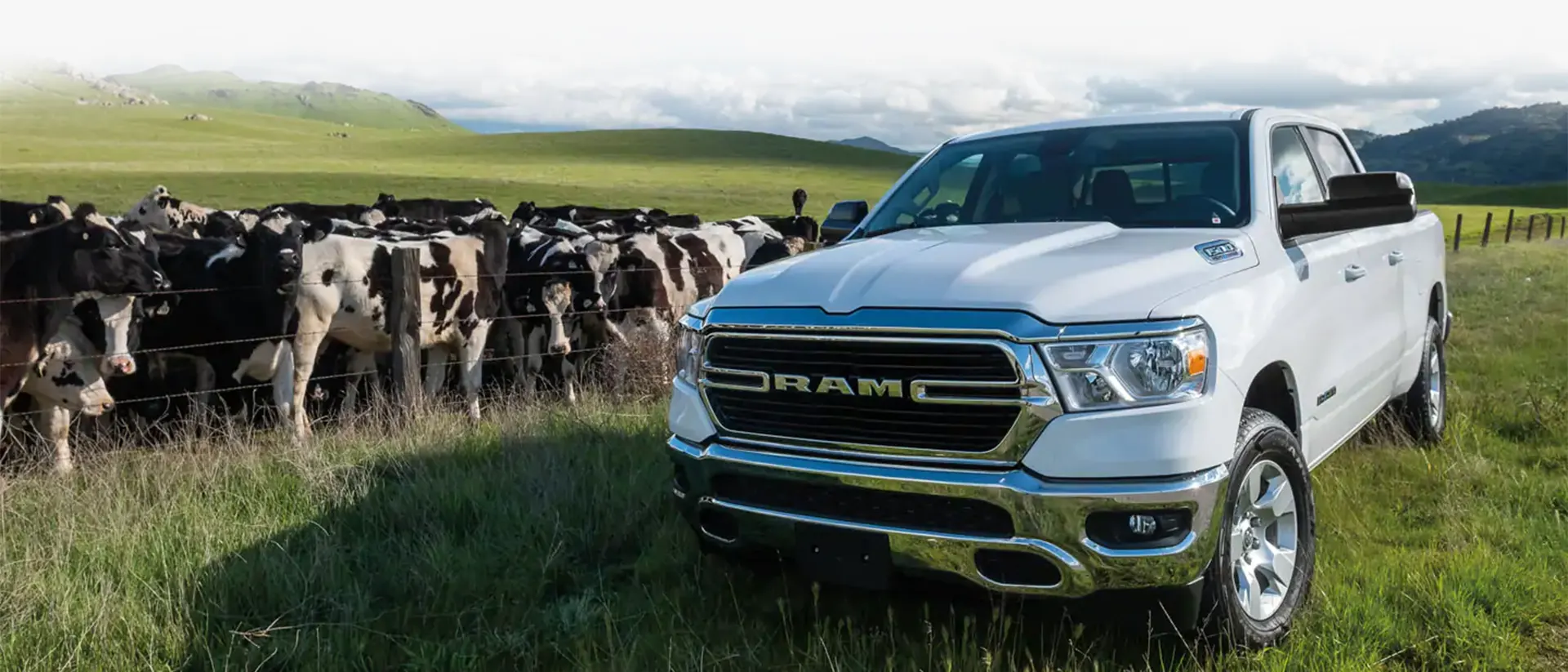 A picture of a Ram 1500 truck in an open field with clouds in the distance.