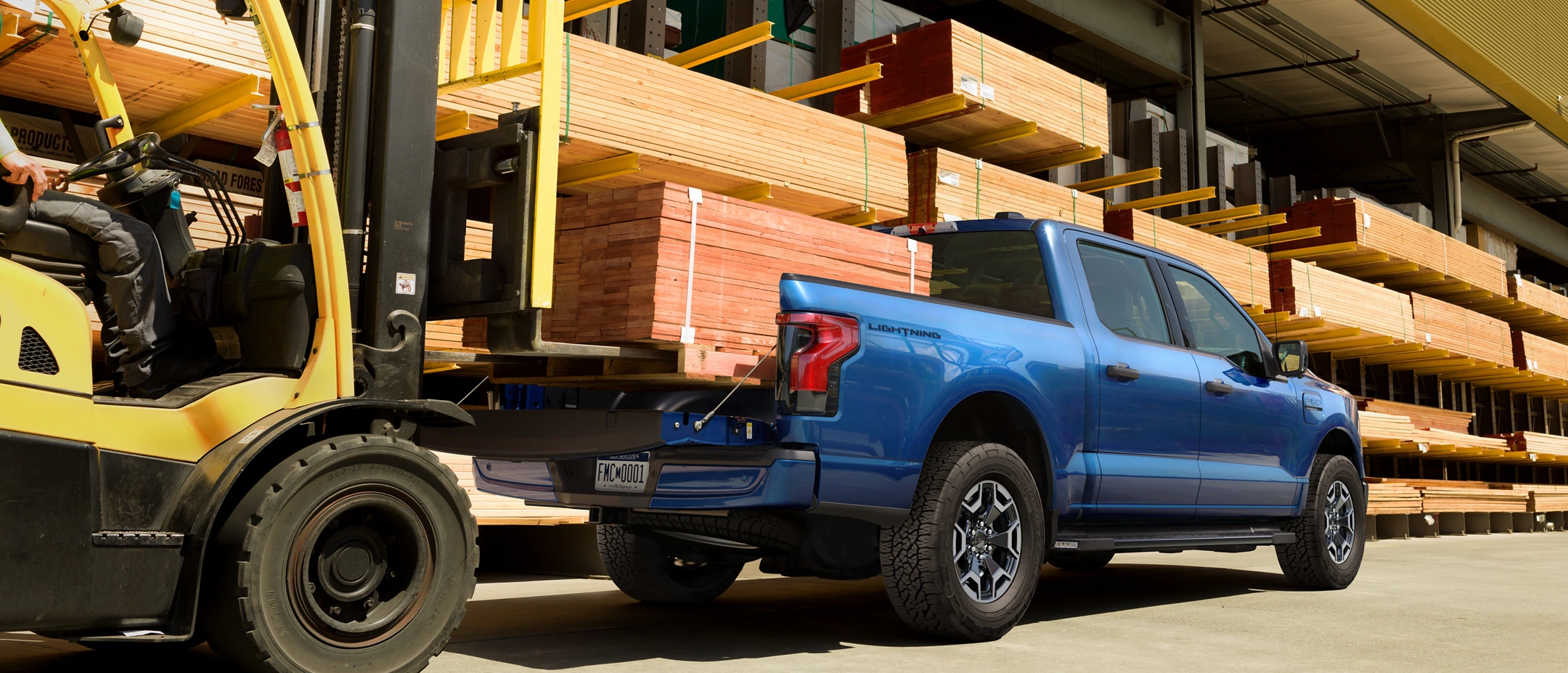Lumber being unloaded into the back of a F-150 Lightning truck