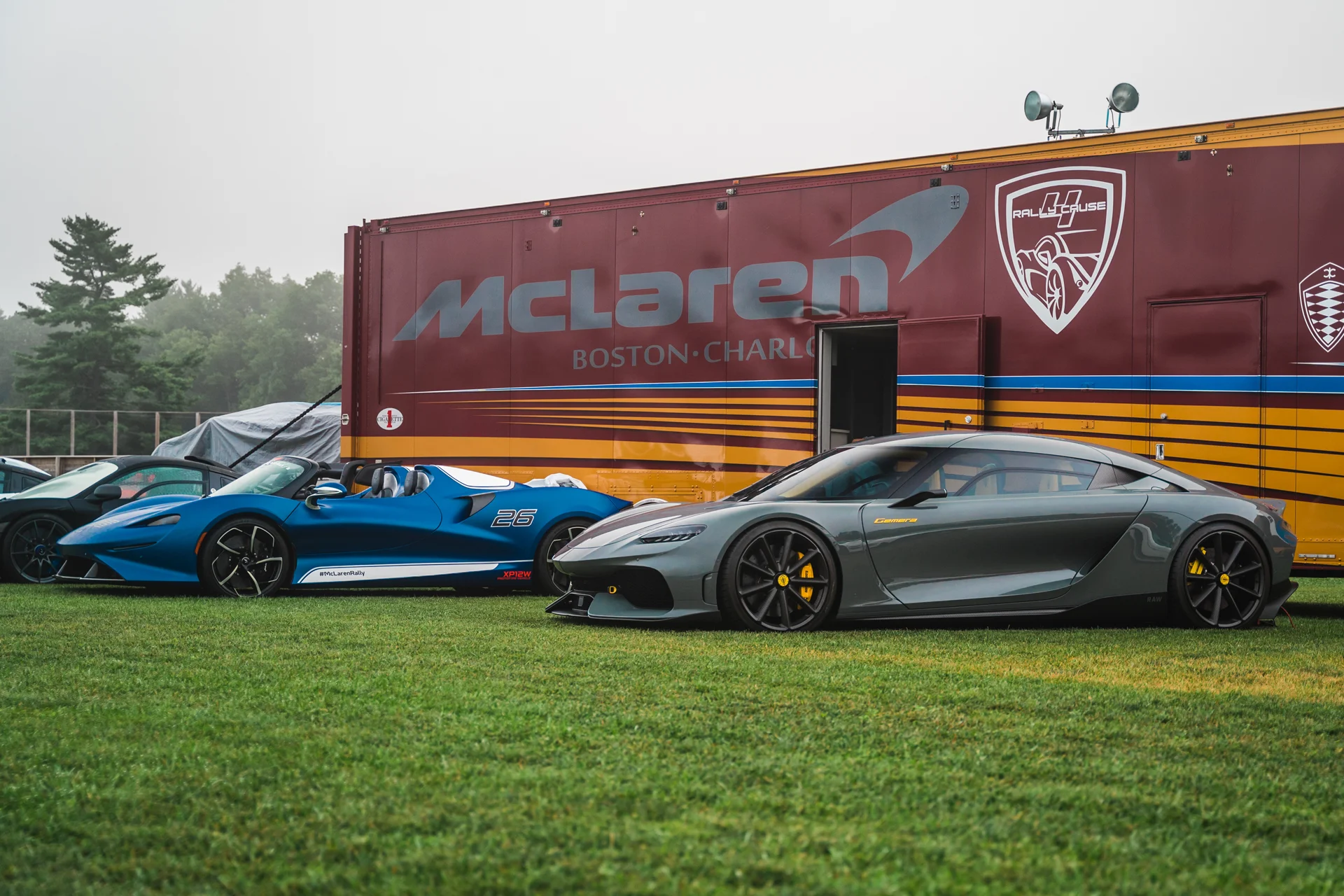 3 McLarens parked in front of a transport truck