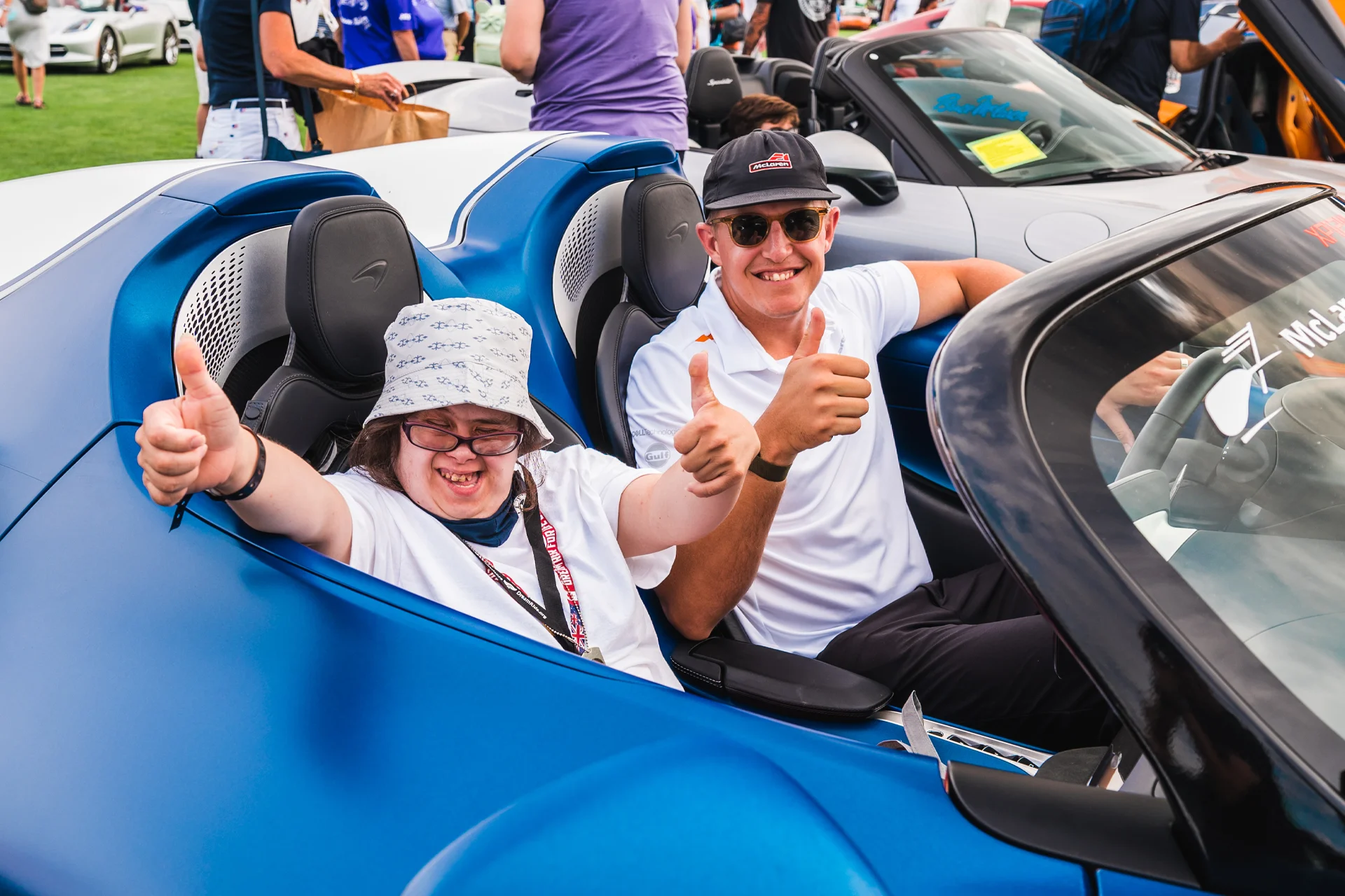 McLaren Boston Dream Ride Experience Smiling guy and girl giving thumbs up in a blue McLaren