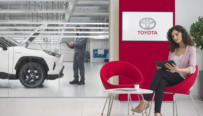 Woman waiting while her car is being looked at by a Toyota Service Technician
