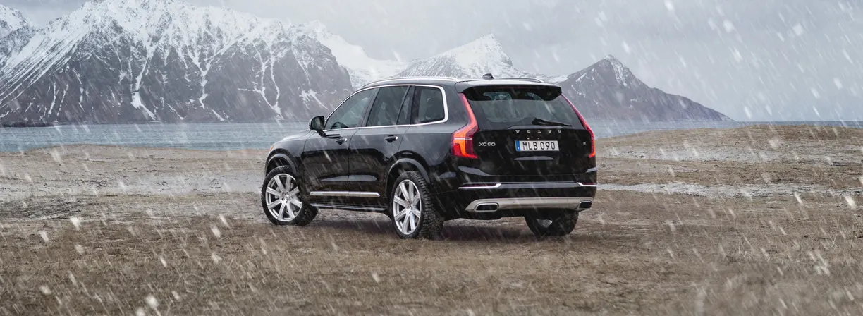 Black Volvo XC90 parked in front of mountains in the snow