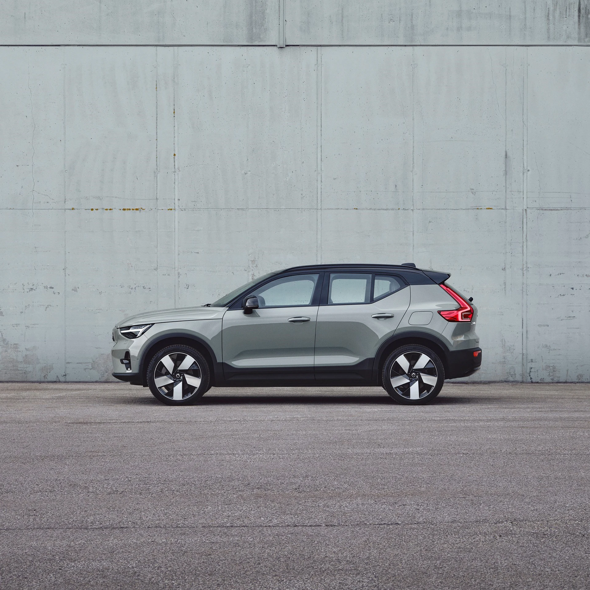 The side profile of a Sage Green Volvo XC40 Recharge SUV plugged into charging station