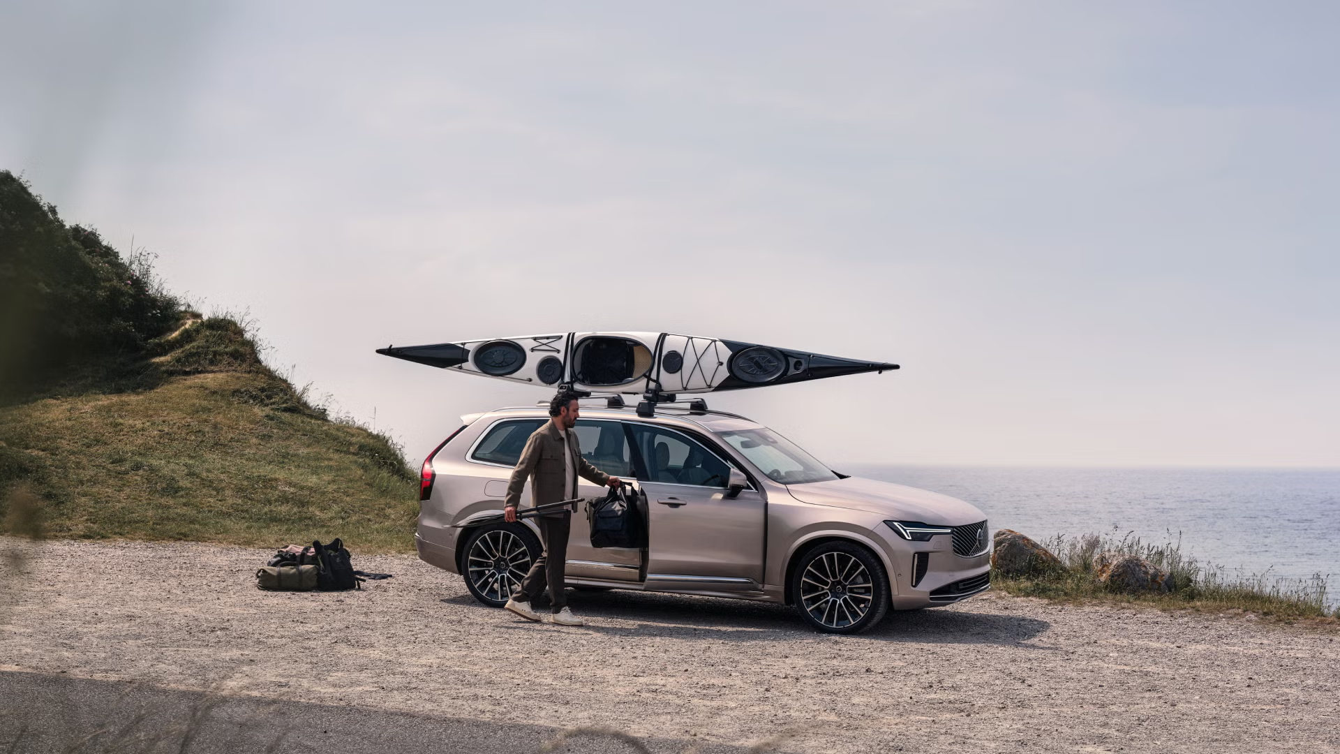 Lifestyle shot of a man loading up a Volvo XC90 mild hybrid with kayaking gear.
